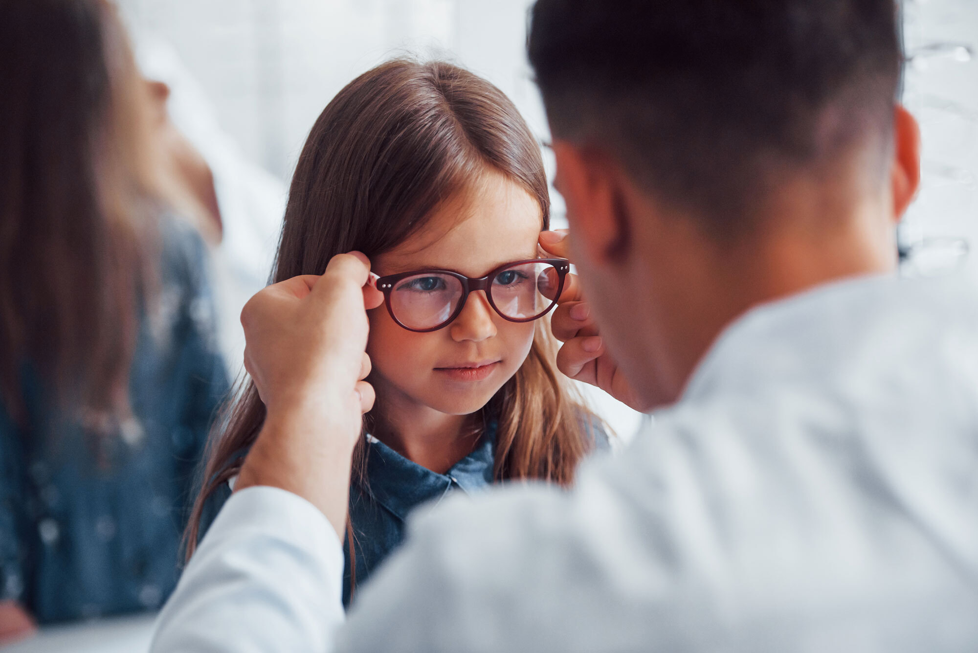 A care provider checks the fit of a child’s glasses.